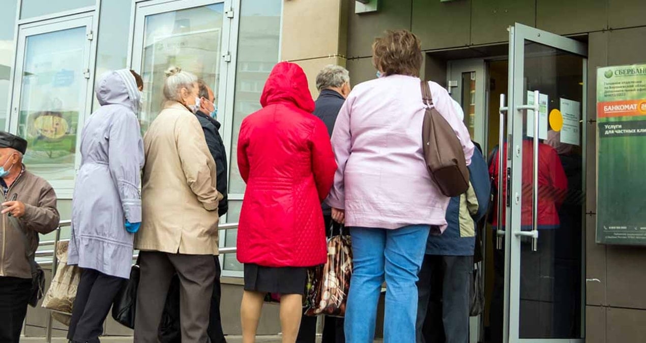 Komşuda bankaların önünde uzun kuyruklar oluştu, herkes elinde dolu zarflar ve çantalarla içeri giriyor